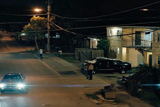 Lens flare as car draws up in neighborhood at night