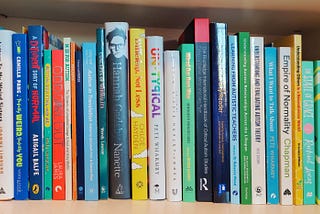 A bookshelf full of books by autistic writers — I’m not up for typing up the full list, sorry! If anyone would be up for doing it for me and sending it over, I’d love that.