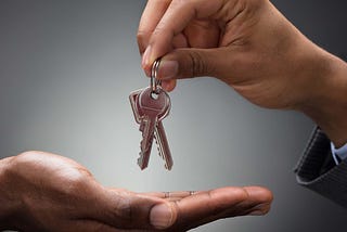 A hand handing off keys to another hand