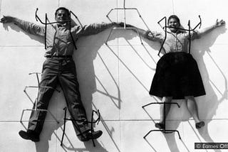 Charles and Ray Eames laying on concrete with limbs between metal pipes (I’m sorry this is a weird pic to explain)