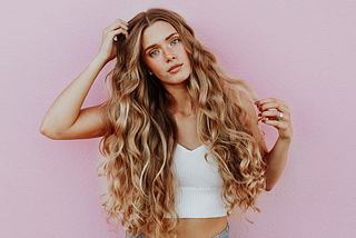 woman-standing-next-to-pink-wall-while-scratching-her-head