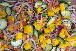 an image of the mago salad, vibrant colors from magoes, jalapenos, red onion cucumbers and tomatoes