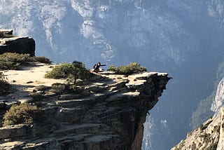 on my knees with one arm reaching out , near the edge of a big cliff in Yosemite