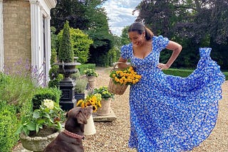 Beautiful lady with her dog, next to her country home surrounded by flowers.