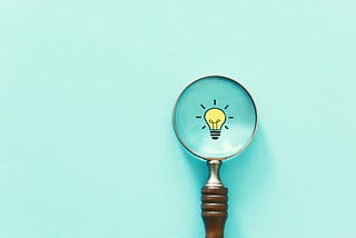 Magnifying glass viewing an illustration of a light bulb.