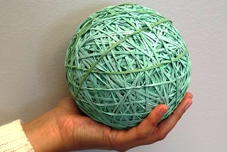 Large ball made of rubber bands in a man’s hand