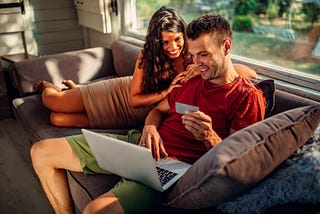 Two people on a couch buying something on a laptop.