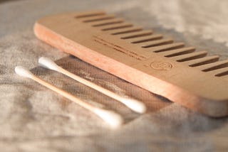 Two cotton buds and a comb laid out on a cloth