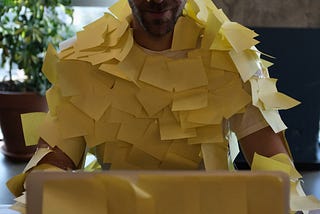 A man and his laptop covered by Post-it notes