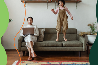 Mom working from home on couch while distracting daughter is jumping on couch