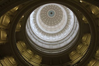 White and brown dome ceiling with a star at the top, inside of the Texas State Capitol building.