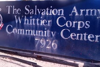 Photo of a blue sign with white text that reads “The Salvation Army Whittier Corps Community Center 7926”