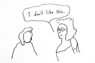 Cartoon: two people facing each other. One the left, person # 1 looking dejected. On the right, a glasses-wearing person is saying, “I don’t like this.”
