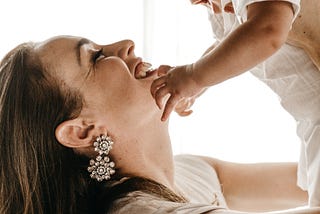 30-something mother smiling and holding baby