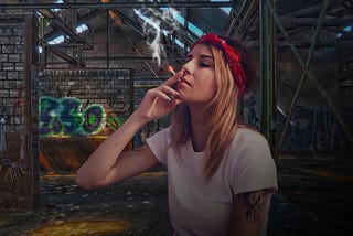 young woman smoking outside a graffiti covered building