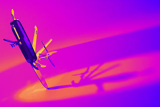 On the left, an open swiss army knife is standing on one blade and looks like it is dancing in a background of orange and purple light.
