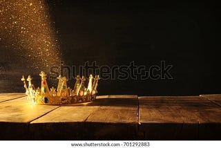 A golden crown embedded with precious stones on a wooden table