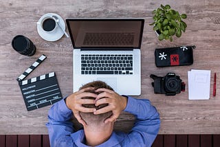 Man bows head in frustration over a laptop computer.