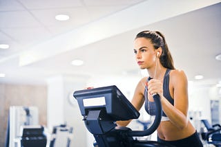 woman on treadmill with earbuds in