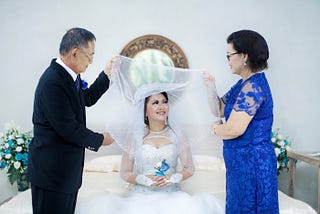 woman-in-wedding-dress-between-older man-in-formal-suit-and-older woman-in-blue-dress