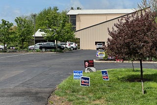 Picture of polling place parking lot with political signs.