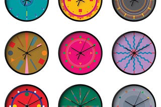 Nine clock with black hands and black edges are pictured, arranged in an evenly spaced grid on a white background. Each clock face has a different geometric, colorful design, on backgrounds that are turquoise, yellow, grey, ochre, hot magenta, lavender, red, green and grey.