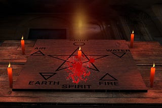 A wooden board with a pentagram and the five ancient elements drawn on it. Four red candles are placed outside of it and a fifth one is placed in the middle, at the center of the pentagram. Some blood is also splattered on it.