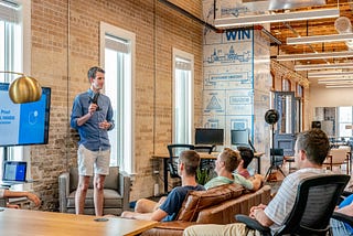 Man standing in front of group of men in office