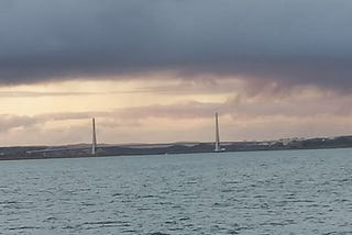 A suspension bridge over water under moody sky