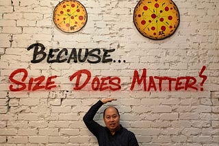 The author in front of the sentence — written on a wall — “Because… Size Does Matter!”