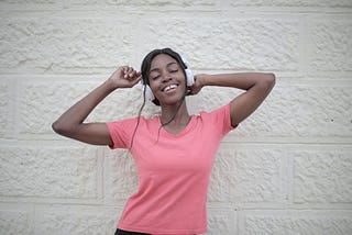 Woman in pink shirt with headphones on dancing to the music