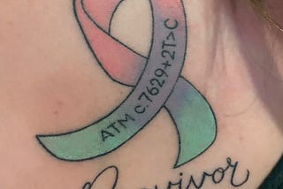 A tattoo shows a multicolored ribbon imprinted with the ATM gene variant, above the word “Previvor.”