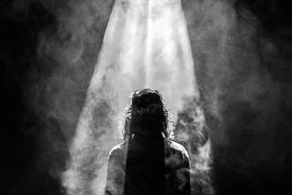 Black and white pic of someone standing in a beam of light