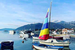 Boat with rainbow mast on lake in Montenegro.