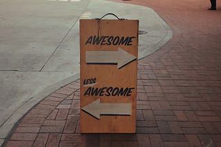 A sign on a walkway with an arrow showing left and one to the right. It reads “awesome” over the arrow leading to the right and “less awesome” over the other.