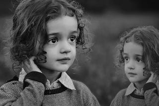 A black and white portrait of a little girl with big eyes and curly hair.