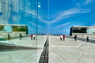 A wide view of the Oslo Opera House, showing the reflections on the glass surfaces.