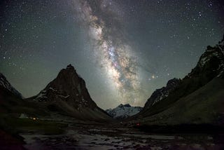 Snowcapped mountains at night time with vivid white starlight connecting the sky and the earth in a Milky Way band