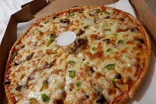 A tasty looking cheese and vegetable topped pizza in a takeaway box