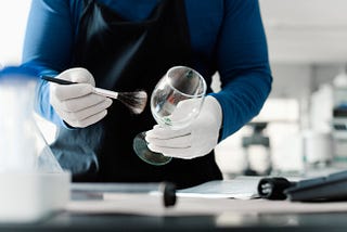 A forensic investigator dusts a wineglass for fingerprints
