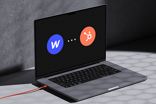 Mockup of the laptop showing Webflow and HubSpot logo on a black background