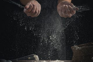 A person sprinkling flour
