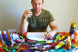 Tim Horan at a desk covered in colored pencils, crayons, and markers.