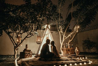 Man & woman in romantic setting, tent, lights and nature