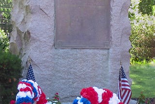A stone memorial with patriotic wreaths and flags decorating it