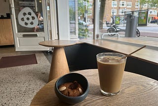 This is a photo of a cup of iced coffee and a cookie on a table in a cafe. You can see a three wheeled electric bike outside, which is mine!