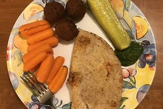 A plate with falafel (chickpea balls), carrots, pickle, whole wheat bread, and chutney.