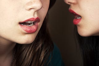 Women with red lipstick gossip together.