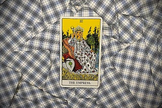 The Empress card, upright, from the Rider-Waite tarot deck on a spread of face down cards.