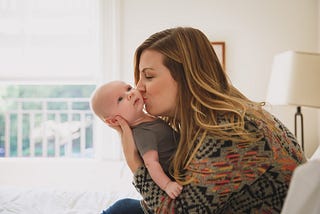 A photo of Chelsey Glasson holding and kissing her baby.